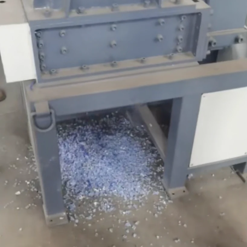 Plastic fragments below the discharge opening of a compact shredder.